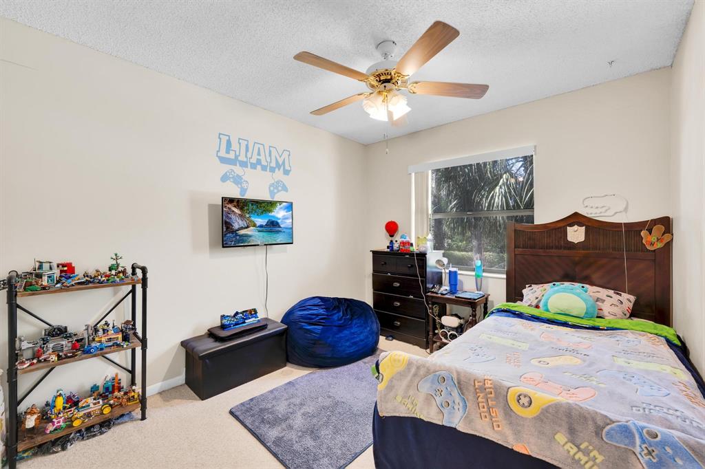 3963 Cocoplum Circle, Unit F Coconut Creek, FL 33063 - Photo 21 of 35 a bedroom with bed and a chandelier