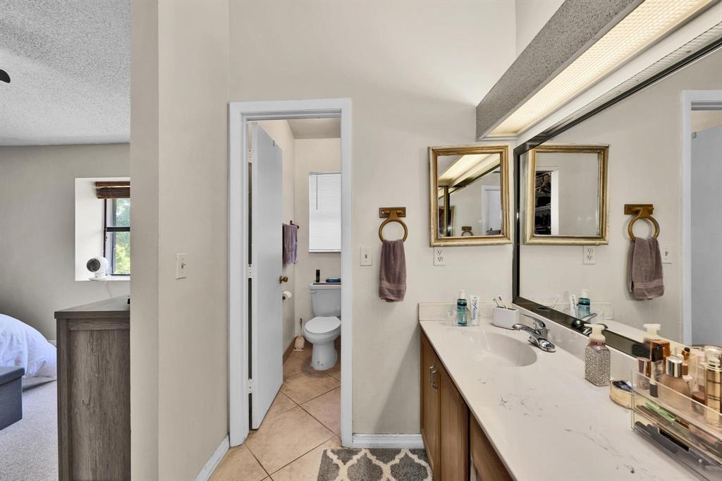 3963 Cocoplum Circle, Unit F Coconut Creek, FL 33063 - Photo 26 of 35 a spacious bathroom with a granite countertop sink mirror and a toilet