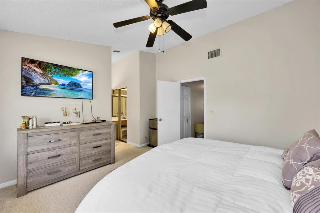 3963 Cocoplum Circle, Unit F Coconut Creek, FL 33063 - Photo 27 of 35 a bedroom with a bed and a chandelier