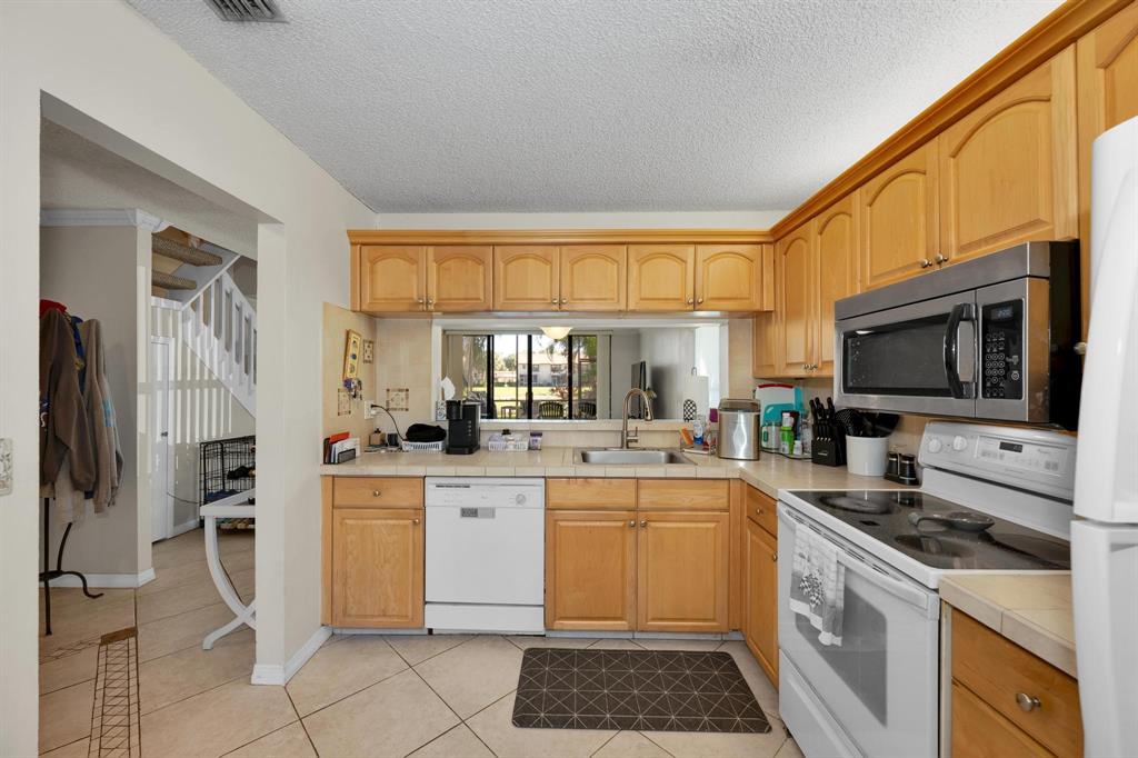 3963 Cocoplum Circle, Unit F Coconut Creek, FL 33063 - Photo 10 of 35 a kitchen with a sink stove and refrigerator