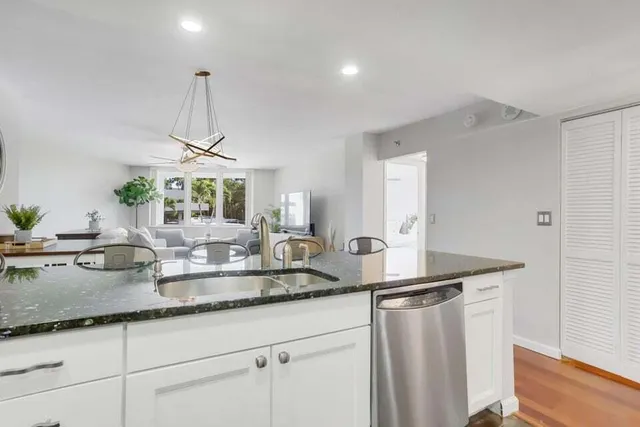 a kitchen with stainless steel appliances granite countertop a sink and a wooden floor
