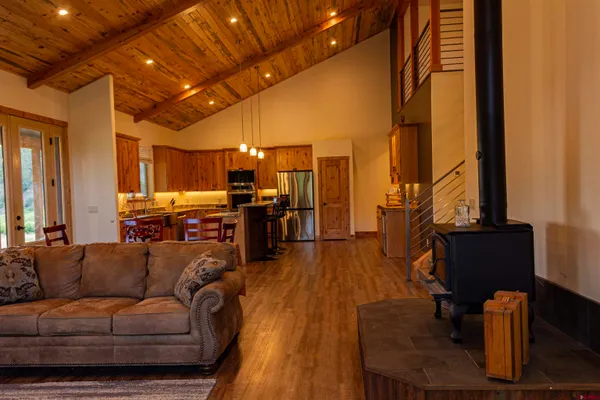 a living room with furniture kitchen view wooden floor and a large window