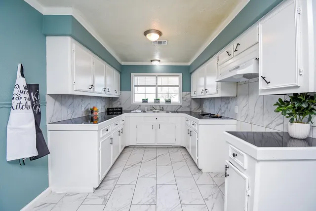 a large white kitchen with stainless steel appliances granite countertop lots of white cabinets a stove a sink and dishwasher
