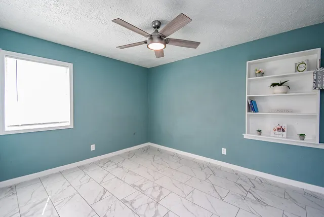a bedroom with a large bed and a chandelier fan