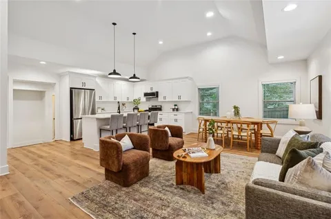 a living room with furniture kitchen view and a large window