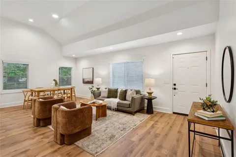 a living room with furniture floor to ceiling window and wooden floor