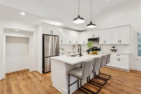 a kitchen with stainless steel appliances a refrigerator a stove sink a center island a stove and cabinets