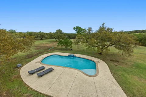 a view of a swimming pool with a yard and plants