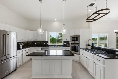 a kitchen with stainless steel appliances granite countertop a stove a sink and a refrigerator