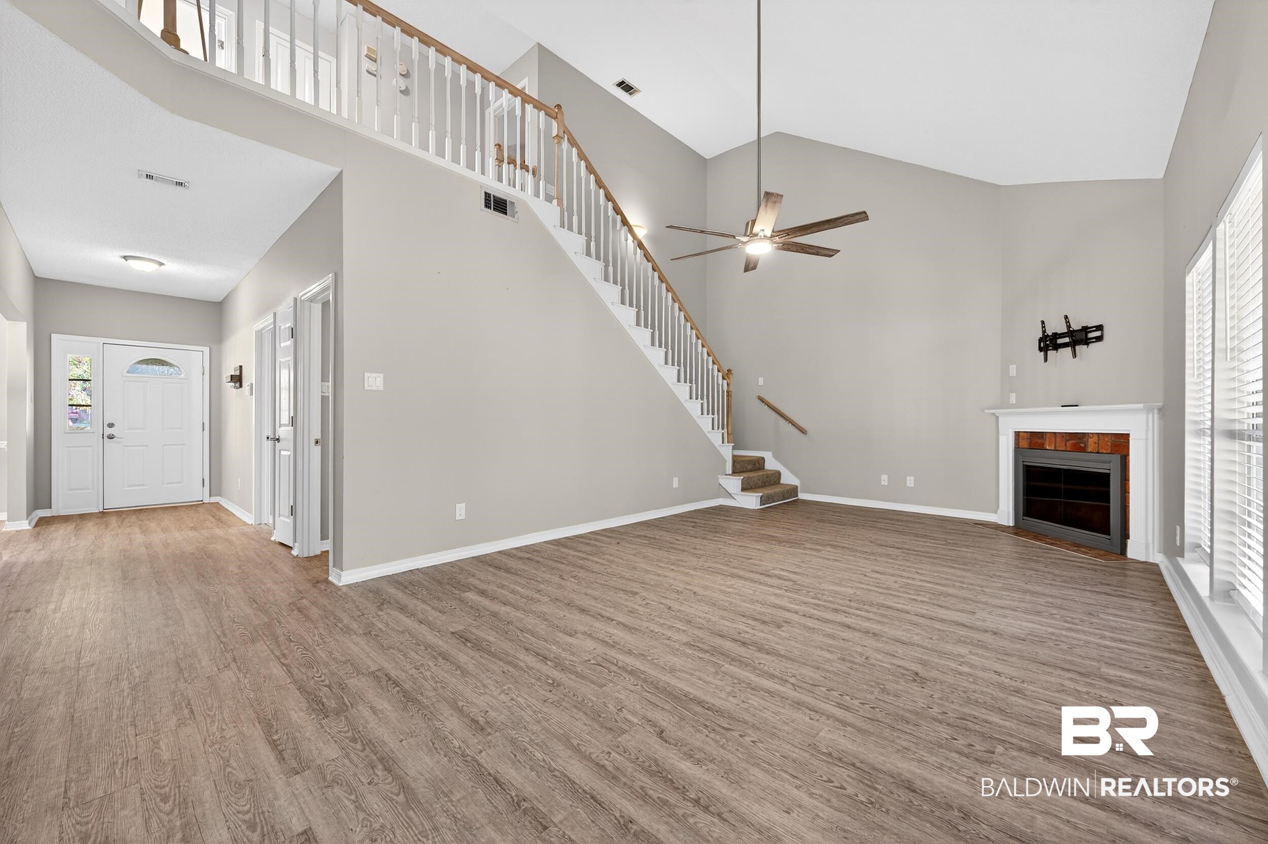 7050 Highpointe Place West Daphne, AL 36527 - Photo 27 of 66 Unfurnished living room with healthy amount of natural light, a fireplace with flush hearth, light wood finished floors, a ceiling fan, and vaulted ceiling