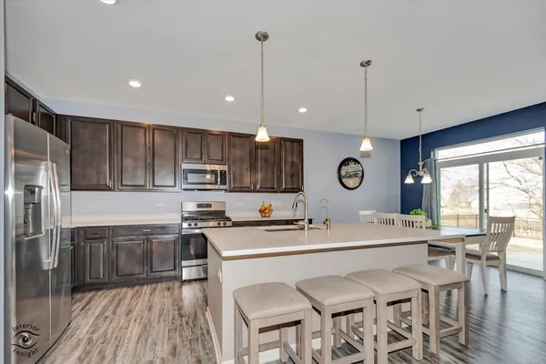 a kitchen with stainless steel appliances granite countertop a sink a stove a refrigerator cabinets and chairs