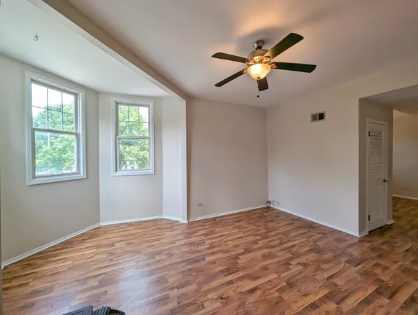 a view of empty room with wooden floor and fan