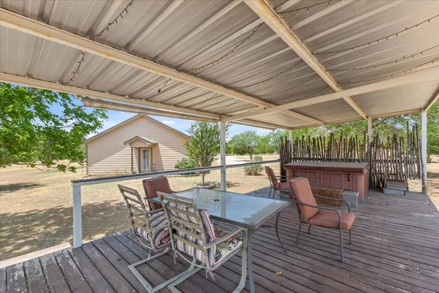 a view of a patio with table and chairs under an umbrella with a barbeque
