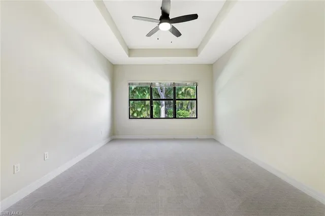 an empty room with windows and ceiling fan
