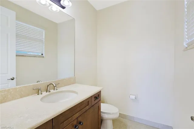 a bathroom with a granite countertop sink and a toilet