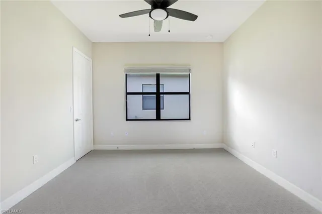 an empty room with windows and ceiling fan