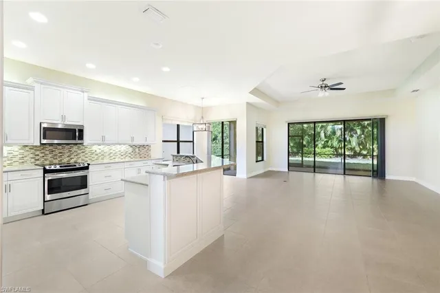 a large kitchen with granite countertop a stove top oven a sink a counter space and cabinets