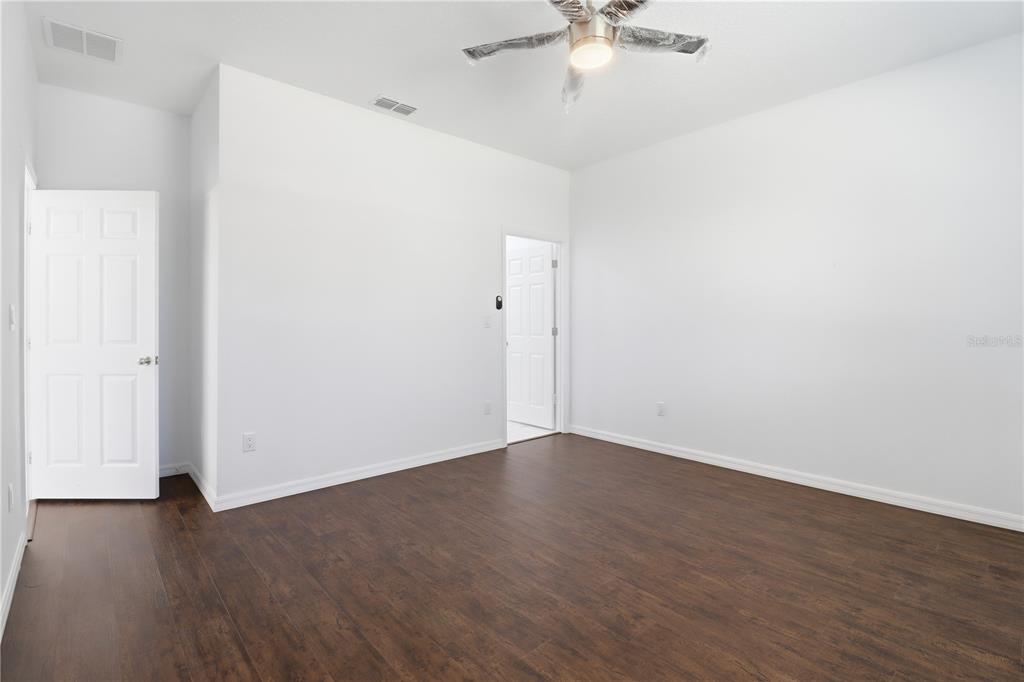 822 Poplar Street Inverness, FL 34452 - Photo 16 of 45 an empty room with wooden floor and fan