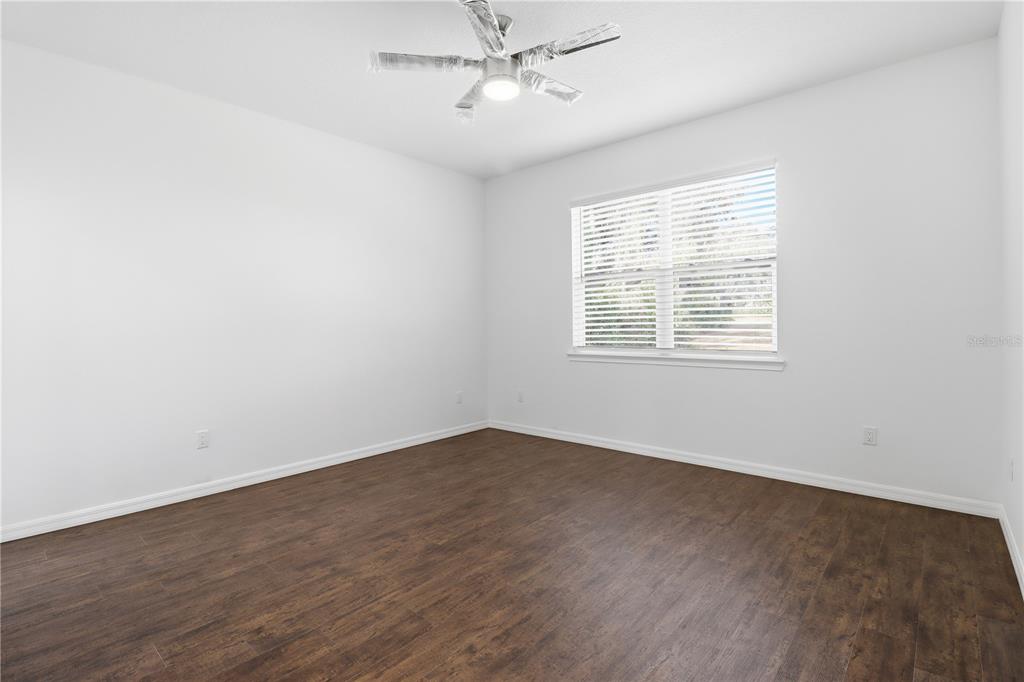 822 Poplar Street Inverness, FL 34452 - Photo 17 of 45 an empty room with wooden floor ceiling fan and windows