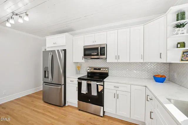 a kitchen with granite countertop stainless steel appliances a refrigerator cabinets and wooden floor