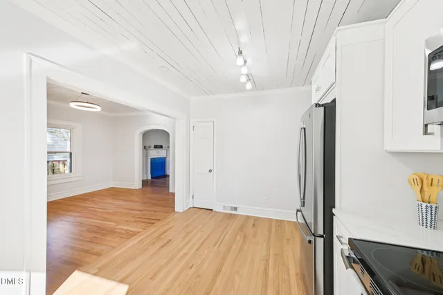 a kitchen with a sink white cabinets and wooden floor