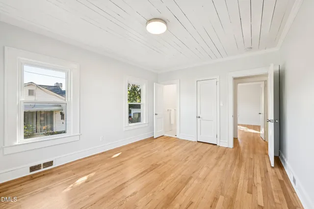 a view of an empty room with window and wooden floor