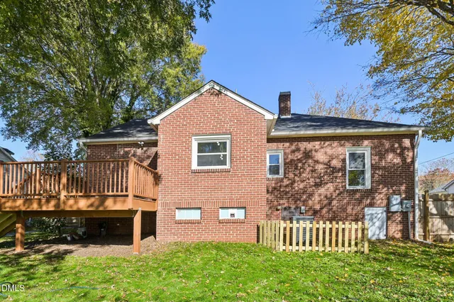 a view of house with backyard and trees in the background