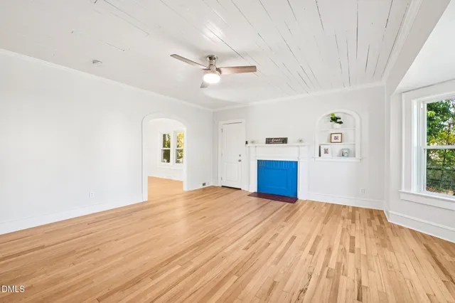 a view of empty room with wooden floor and ceiling fan
