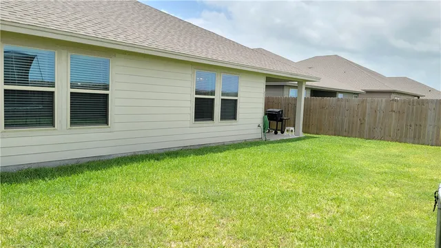 a backyard of a house with yard and wooden fence
