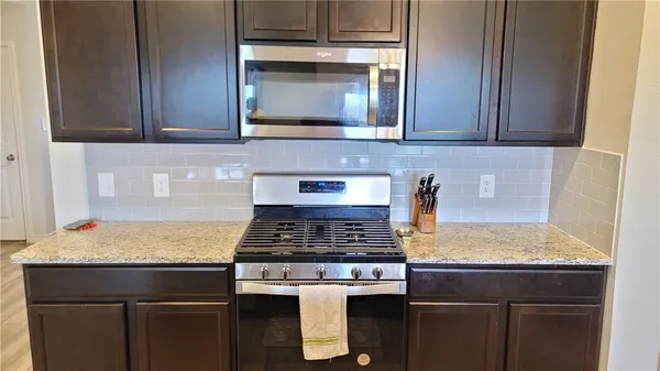 a kitchen with stainless steel appliances granite countertop a stove and a microwave