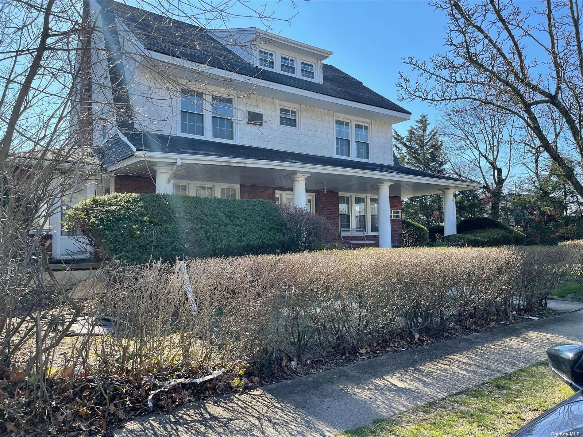 87 Prospect Avenue Cedarhurst, NY 11516 - Photo 1 of 15 a front view of a house with a yard and garage