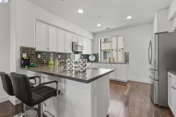 a kitchen with stainless steel appliances granite countertop a refrigerator sink and white cabinets