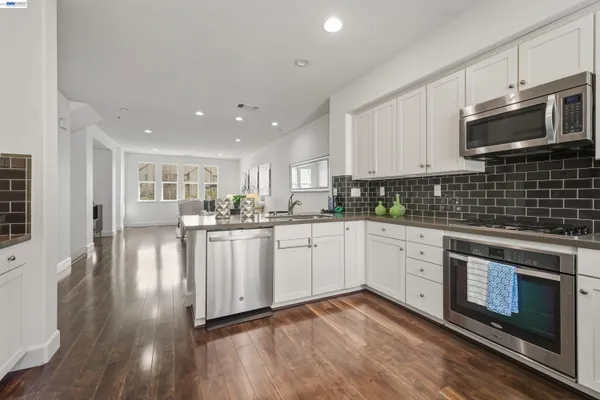 a kitchen with stainless steel appliances granite countertop a stove a sink and a microwave