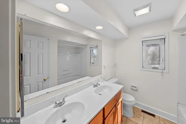 a spacious bathroom with double vanity sink a mirror and a toilet