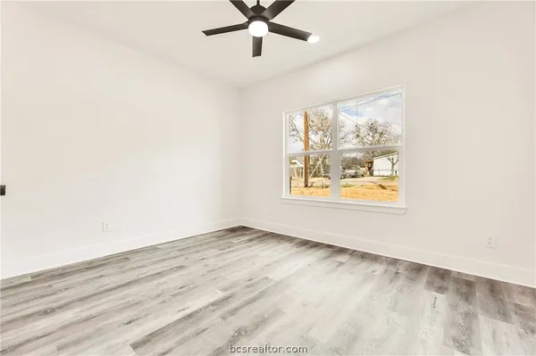 an empty room with wooden floor and windows
