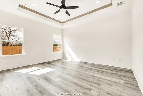 a view of empty room with wooden floor and fan