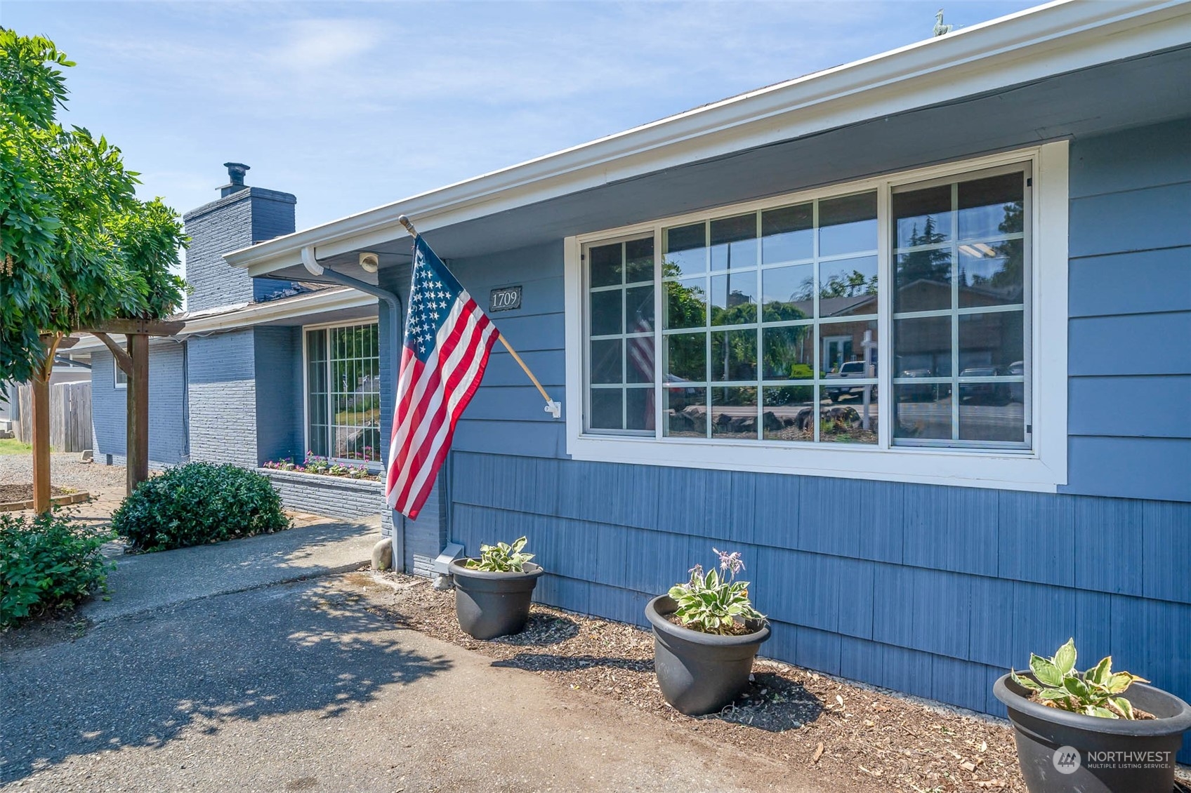 a front view of a house with a yard and potted plants