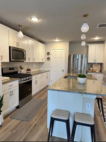 a kitchen with stainless steel appliances granite countertop a sink a stove top oven a counter space and cabinets