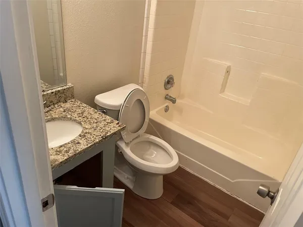 a bathroom with a granite countertop toilet sink and mirror