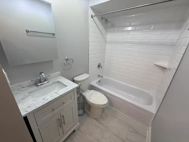 a bathroom with a granite countertop sink toilet and shower