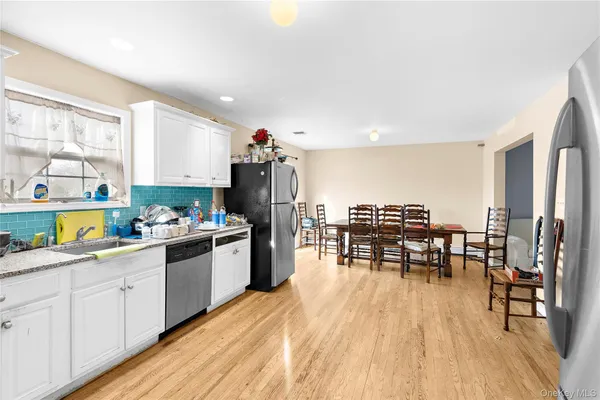 a kitchen with a table chairs wooden floors and a view of living room