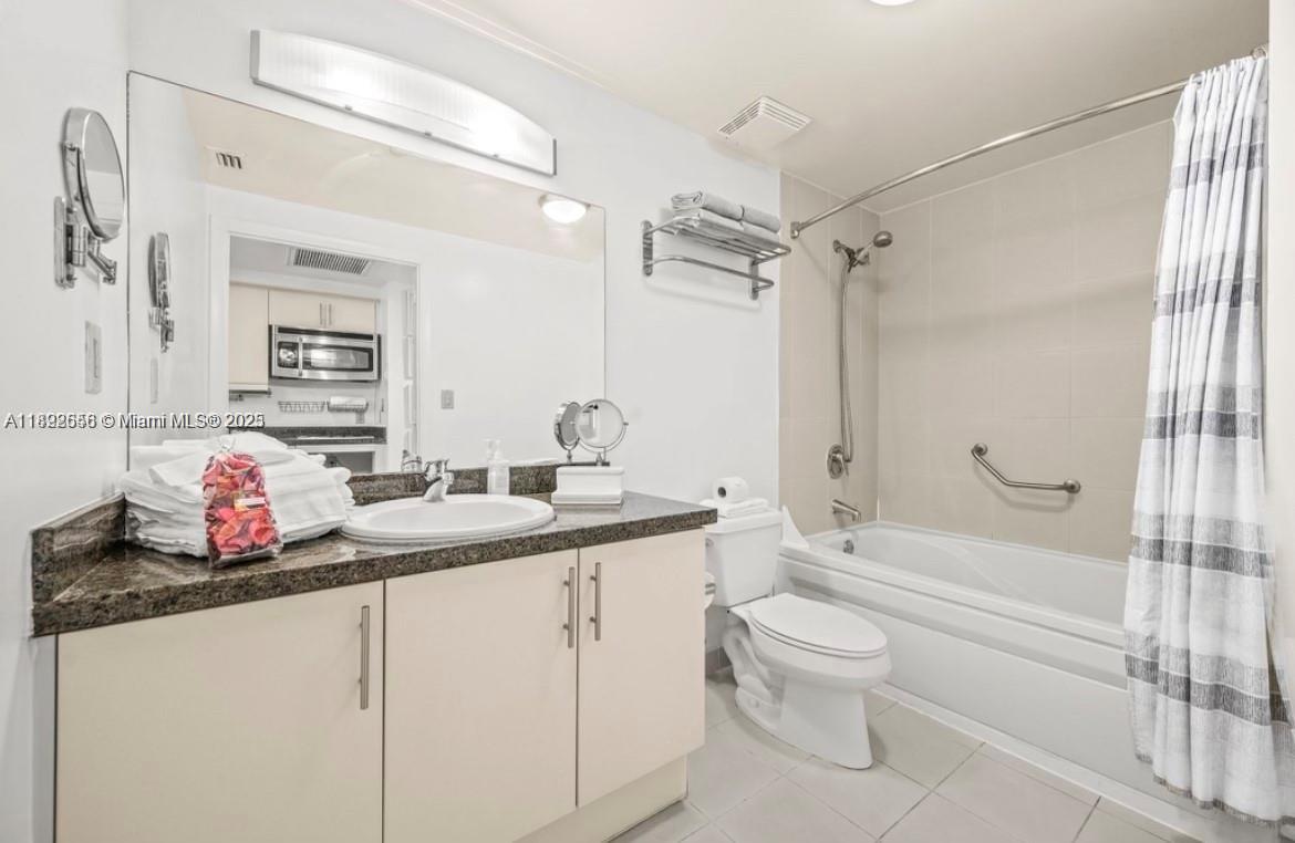 2889 McFarlane Road, Unit 909 Miami, FL 33133 - Photo 34 of 36 a bathroom with a granite countertop sink a toilet and a mirror