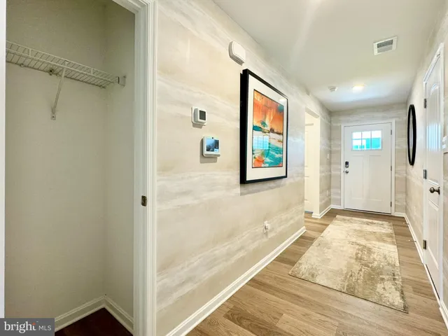 a view of a hallway with wooden floor and a bathroom