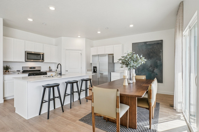 2097 North Ostler Peak Road, Unit 115 Heber City, UT 84032 - Photo 26 of 33 Open-concept kitchen and dining area featuring white cabinetry, a kitchen island with seating, stainless steel appliances, and light wood-finish flooring