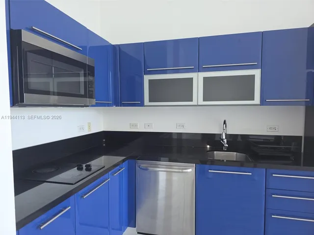 a kitchen with granite countertop cabinets stainless steel appliances and a microwave oven