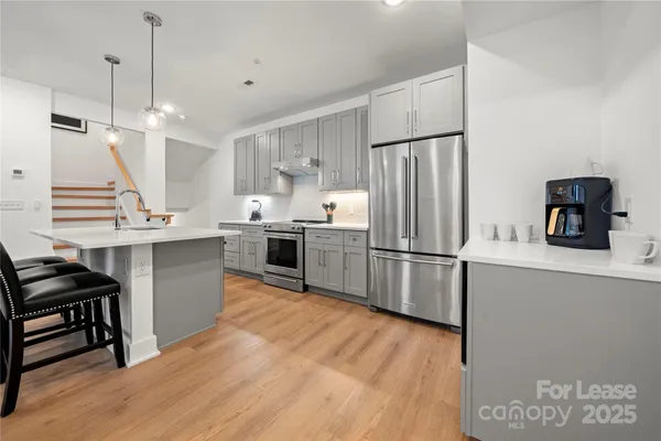 a kitchen with stainless steel appliances granite countertop a refrigerator a sink dishwasher a stove and a refrigerator