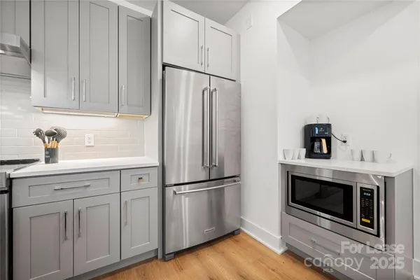 a kitchen with white cabinets stainless steel appliances and wooden floor