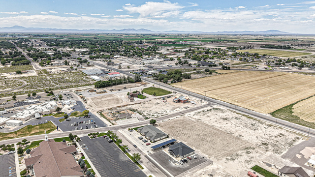 84 White Sage Avenue, Unit 2 Delta, UT 84624 - Photo 16 of 18 Expansive aerial landscape featuring a mix of developed and undeveloped land, established tree-lined streets, distant mountain ranges, and numerous paved parking areas