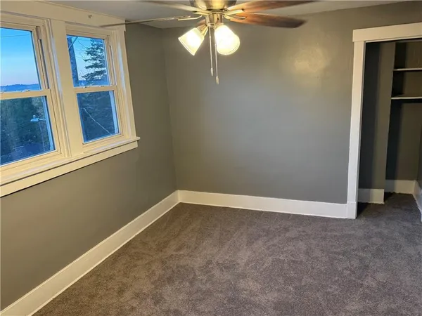 an empty room with windows and fan