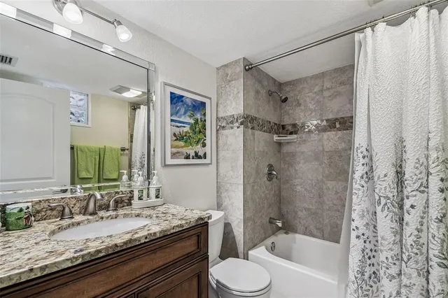 a bathroom with a granite countertop sink toilet and shower